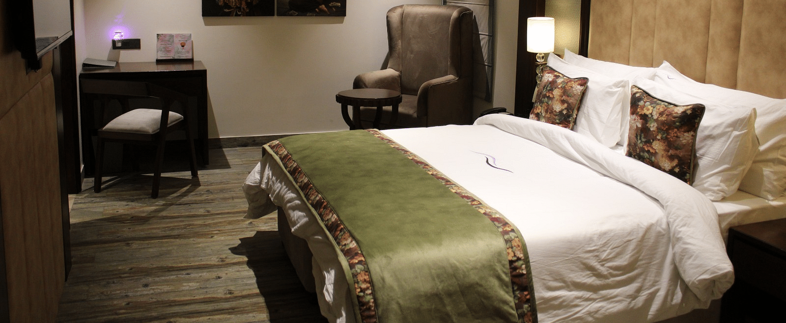 Side view of a bedroom featuring a working table, a chair, and portraits adorning the wall at BluSalzz Residence, Amritsar